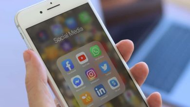 وسائل التواصل الاجتماعي - يد تمسك بهاتف محمول يعرض تطبيقات الوسائل الاجتماعية